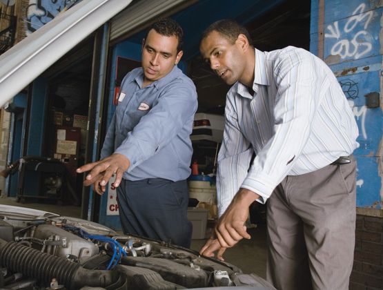 Mechanic and customer looking at engine